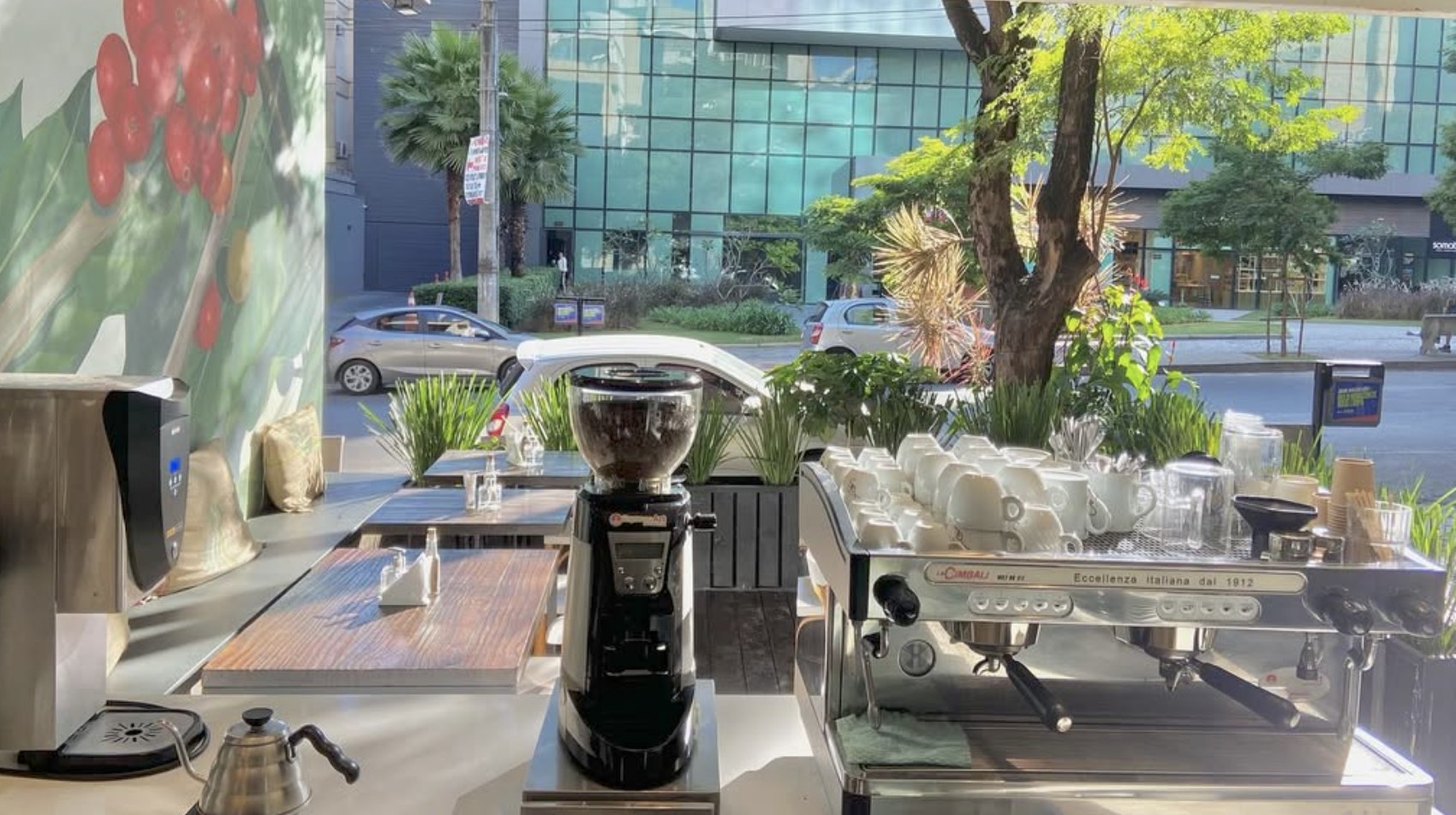 The espresso bar and grinder against a coffee cherry mural at Yes, Nós Temos Café